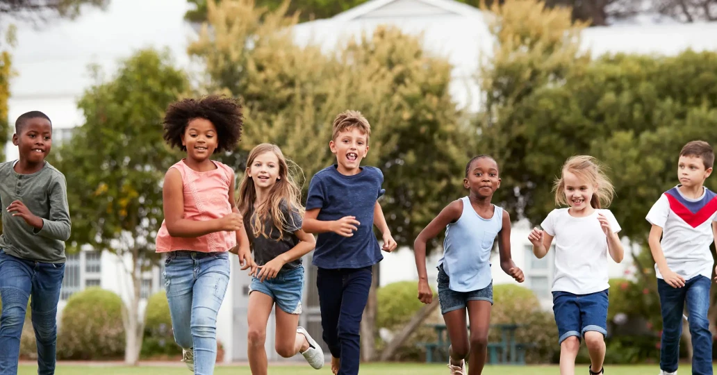 A group of children running joyfully in a park, showcasing energy and happiness in a natural setting