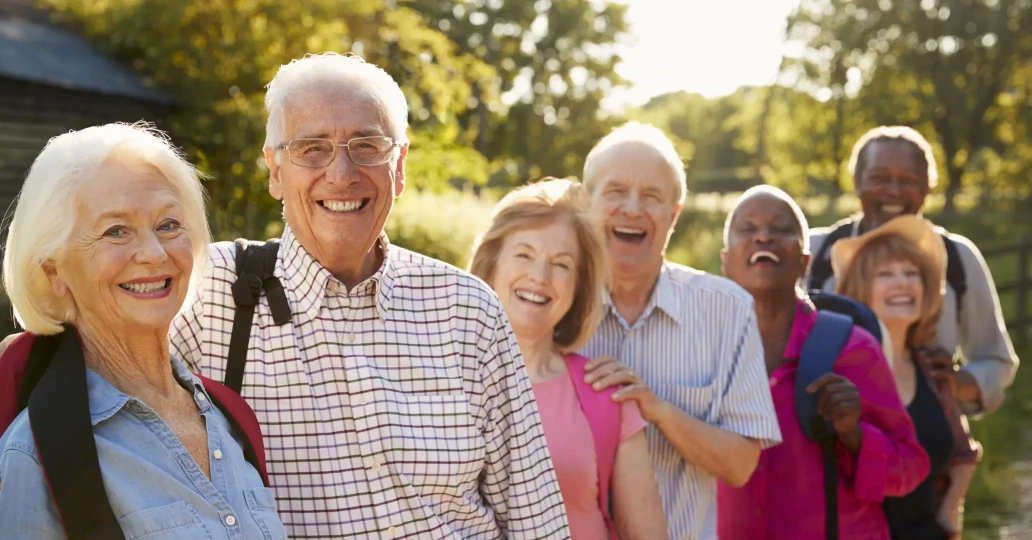 Group of joyful seniors enjoying a sunny day outdoors, laughing and walking together, showcasing active and happy aging