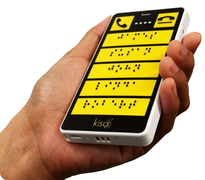 Person holding a bright yellow KISA assistive device featuring tactile Braille buttons